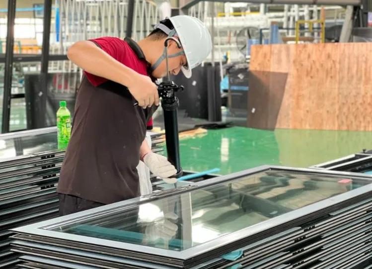 Worker assembling glass panel into aluminum frame